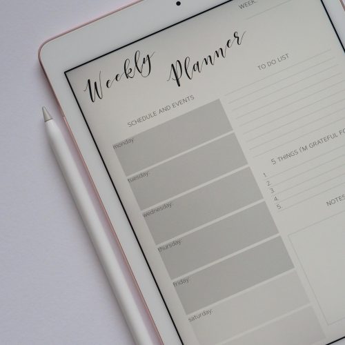 White background graphic - table with pink iPad and Apple Pencil on it with a digital planner on the screen